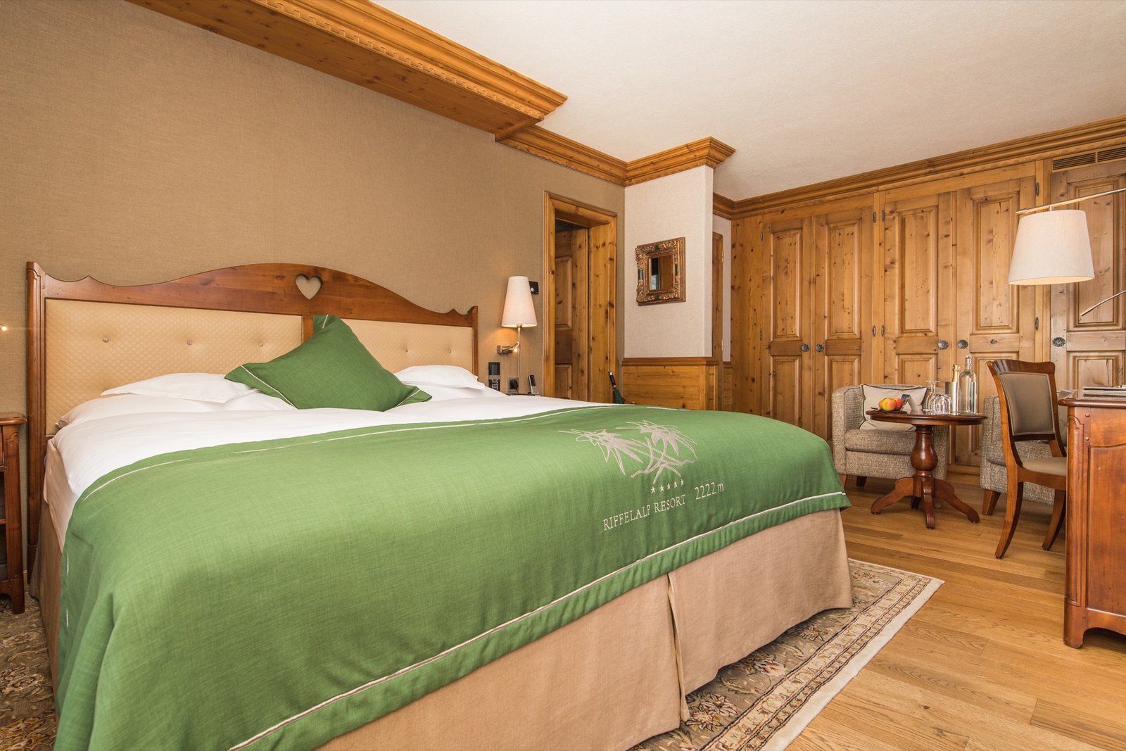 Riffelalp Resort alpine room with warm wood interiors and green bed linen